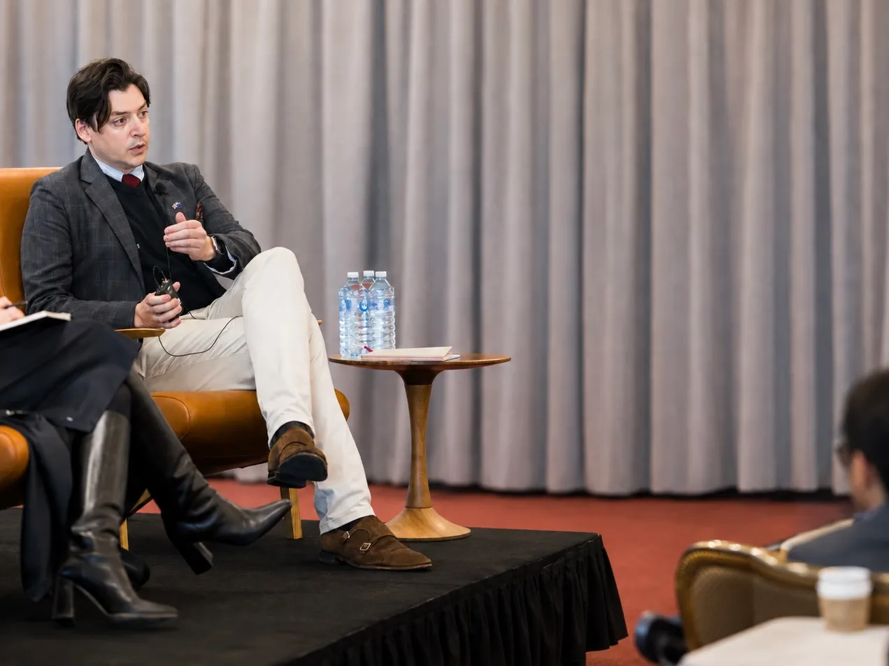 Al Hynes speaking while seated on stage at a professional event